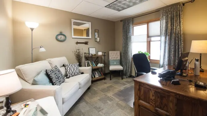 Interior counseling office with comfortable seating, desk workspace, natural lighting, and professional decor