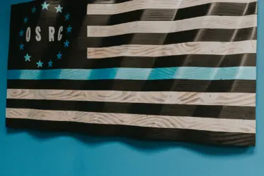Interior wall decoration with wooden flag-style art featuring OSRC initials and striped design on teal background