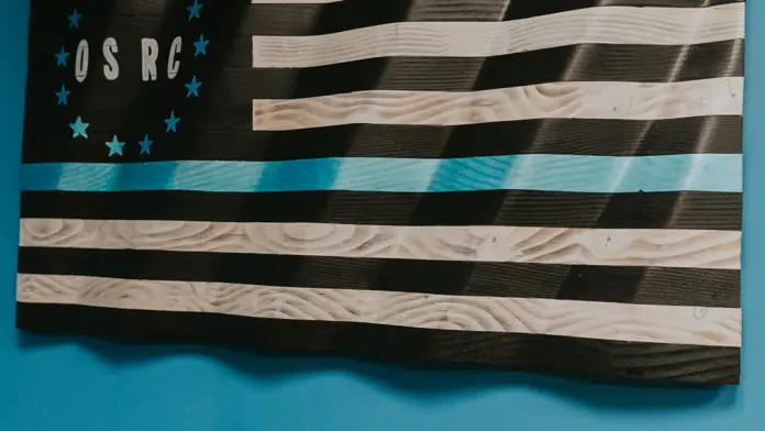 Interior wall decoration with wooden flag-style art featuring OSRC initials and striped design on teal background
