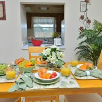 Interior dining area with yellow table, fresh produce and vegetables displayed, window overlooking grounds