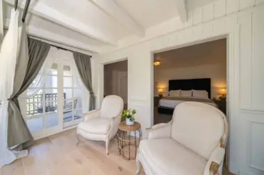 Interior luxury bedroom with upholstered headboard bed, leather seating chair, fireplace, and framed mountain landscape artwork