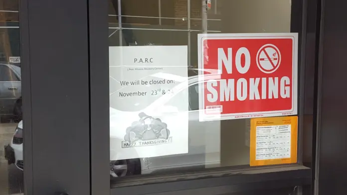 Exterior entry door with no-smoking sign, P.A.R.C facility closure notice, and informational postings on glass