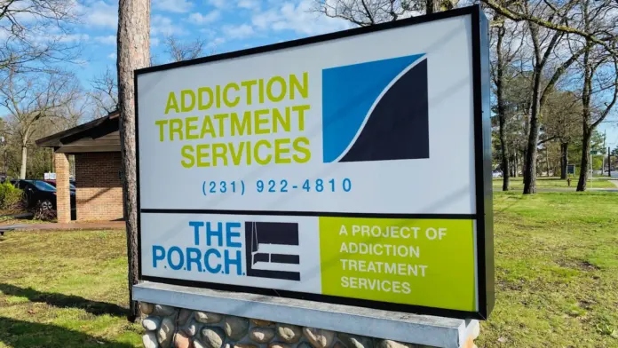 Outdoor ground sign displaying facility name, phone number, and program names in green and blue colors
