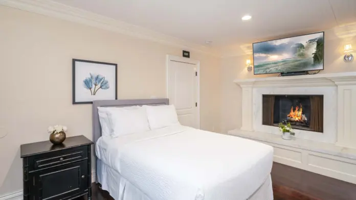 Interior hallway with staircase, white paneling, wooden handrails, framed certifications on wall, and pendant lighting