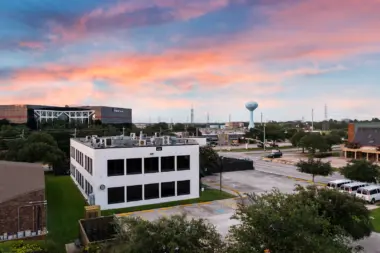 Exterior view of multi-story white and brick treatment facility with parking lot and landscaping visible at dusk