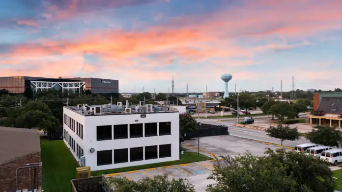 Exterior view of multi-story white and brick treatment facility with parking lot and landscaping visible at dusk