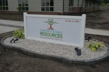 Exterior signage displaying Community & Family Resources logo and address with landscaping