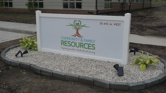 Exterior signage displaying Community & Family Resources logo and address with landscaping