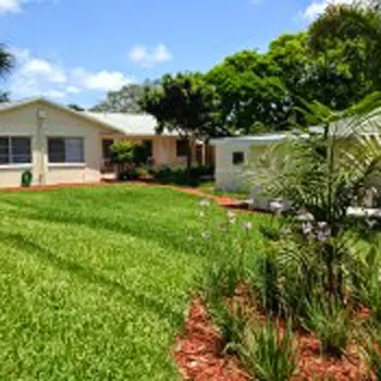 Exterior view of treatment facility grounds showing manicured lawn, shrubs, building structure, and mature trees