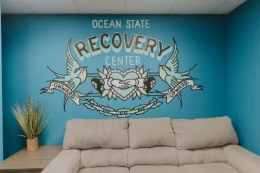 Interior wall mural featuring Ocean State Recovery Center logo with decorative wings and heart design on teal background