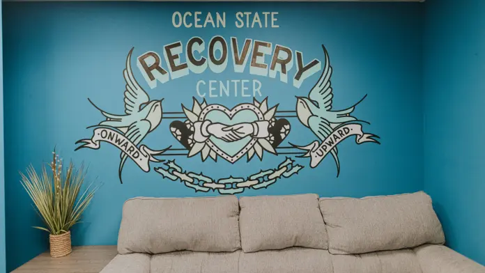 Interior wall mural featuring Ocean State Recovery Center logo with decorative wings and heart design on teal background