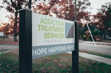 Close-up of directional sign post with facility name, location, and hope-focused messaging at dusk