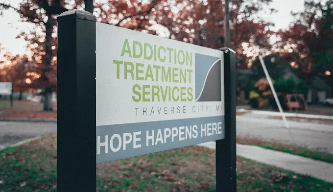 Close-up of directional sign post with facility name, location, and hope-focused messaging at dusk
