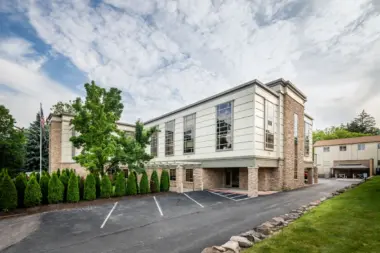 Exterior view of treatment facility with brick and stone facade, large windows, landscaping, and parking area
