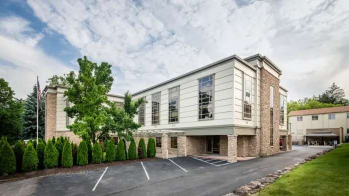 Exterior view of treatment facility with brick and stone facade, large windows, landscaping, and parking area