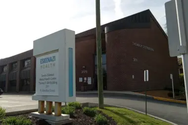 Exterior view of brick mental health center building with parking lot, entrance, and directional signage