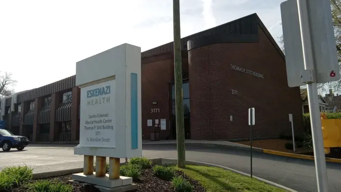 Exterior view of brick mental health center building with parking lot, entrance, and directional signage