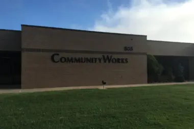 Front exterior of Community Works facility showing brick building facade with address number 805 and facility name signage