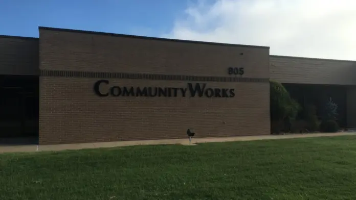 Front exterior of Community Works facility showing brick building facade with address number 805 and facility name signage
