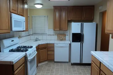 Outdoor garden area featuring wooden arbor with magenta flowering vines and surrounding landscaped pathways