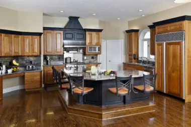 Interior kitchen with wood cabinetry, central island, stainless steel appliances, and hardwood flooring throughout space