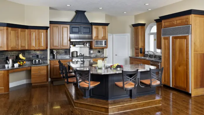 Interior kitchen with wood cabinetry, central island, stainless steel appliances, and hardwood flooring throughout space