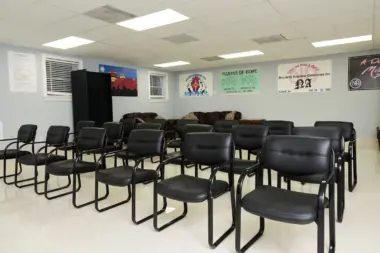 Interior meeting room with arranged black leather chairs, facility signage, wall-mounted program information displays