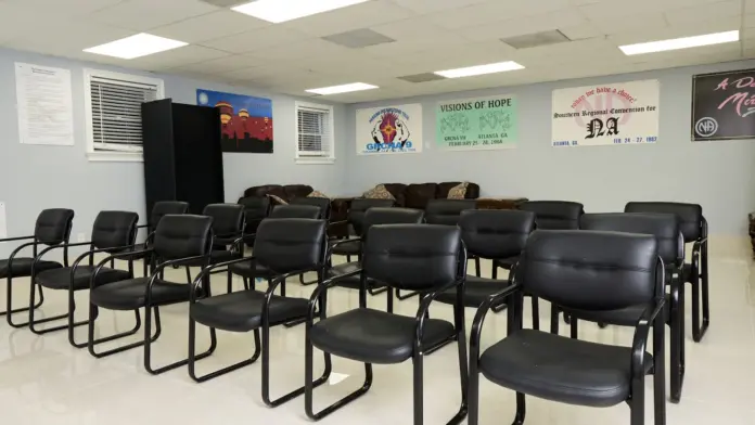 Interior meeting room with arranged black leather chairs, facility signage, wall-mounted program information displays