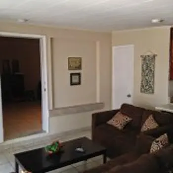 Interior hallway with white walls, open doorway, black furniture, and access to common areas