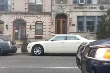 Front facade of Integrity House with ornate stone detailing, arched entry, and street-level parking