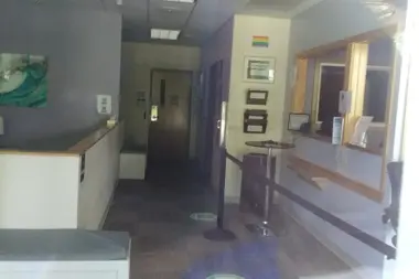 Interior corridor showing reception counter, walls with artwork, doors, and office windows