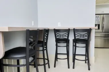 Interior kitchen with counter seating, black bar stools, stainless steel appliances, and cabinetry