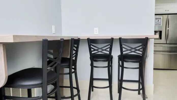 Interior kitchen with counter seating, black bar stools, stainless steel appliances, and cabinetry