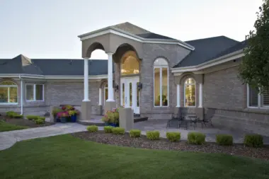 Exterior front of residential treatment center with brick construction, white columns, arched entryway, and landscaped grounds