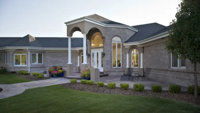 Exterior front of residential treatment center with brick construction, white columns, arched entryway, and landscaped grounds