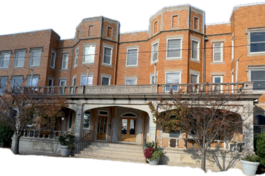Exterior view of brick treatment facility showing main entrance with stone archway, multiple stories, and landscaped grounds