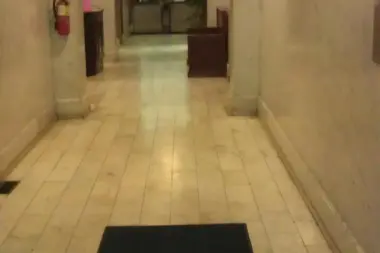 Interior hallway featuring arched ceilings, pink and cream walls, recessed lighting, framed artwork, and entrance door at corridor end