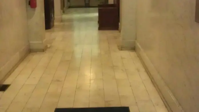 Interior hallway featuring arched ceilings, pink and cream walls, recessed lighting, framed artwork, and entrance door at corridor end