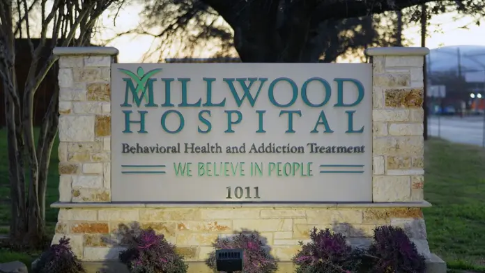 Exterior stone monument sign displaying Millwood Hospital name and behavioral health services with landscaping