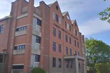 Exterior view of multi-story red brick treatment facility building with white-trimmed windows, peaked roofline, and signage.