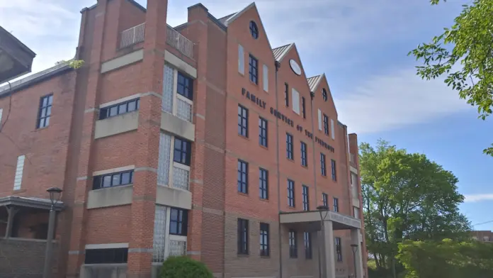 Exterior view of multi-story red brick treatment facility building with white-trimmed windows, peaked roofline, and signage.