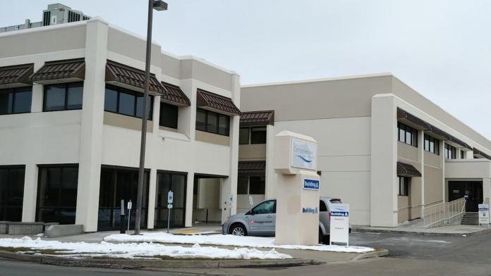 Exterior of modern treatment facility showing multi-story building facade, main entrance, windows, and front parking area in winter