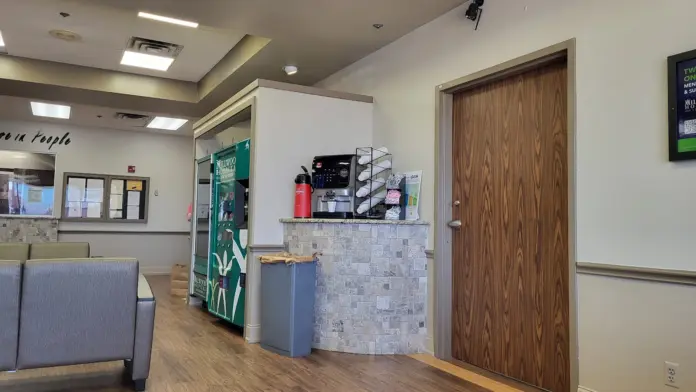 Interior lobby showing reception counter, waiting seating, medication dispensing area, and hallway entrance with modern fixtures