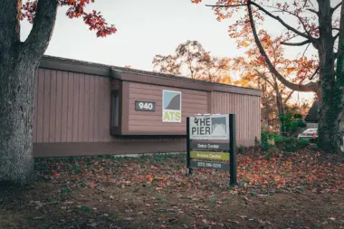 Exterior metal building with rust-colored siding and signage for detox services surrounded by trees