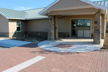 Exterior residential building with stone veneer, brick walls, wide porch cover and brick courtyard paving