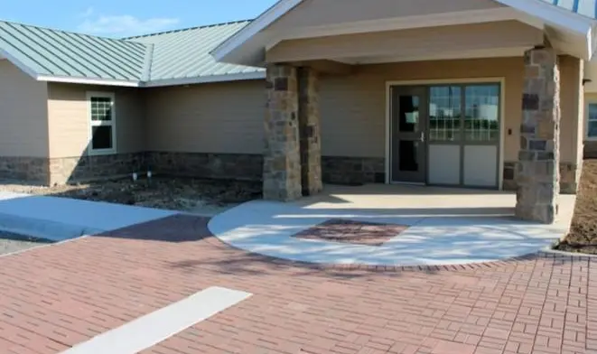 Exterior residential building with stone veneer, brick walls, wide porch cover and brick courtyard paving