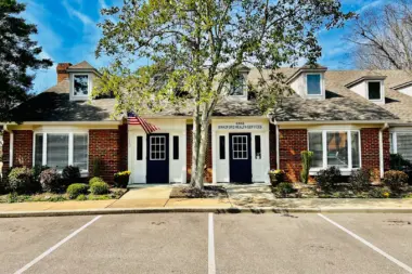 Exterior view of residential-style treatment facility with multiple entrance doors, dormers, and Bradford Health Services signage from parking area.