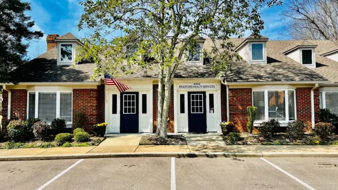Exterior view of residential-style treatment facility with multiple entrance doors, dormers, and Bradford Health Services signage from parking area.