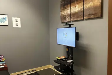 Interior office area with computer monitor, keyboard, and mounted equipment on wall