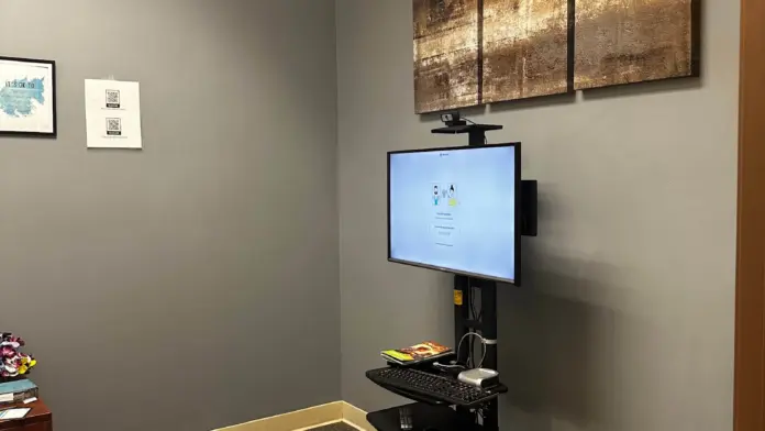 Interior office area with computer monitor, keyboard, and mounted equipment on wall